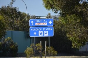 Road signs directing to Murdoch Hospital and Station in a green suburban area.