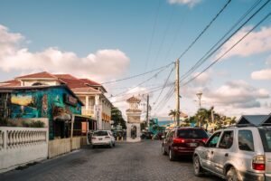 Sunny street scene with a clocktower and vibrant murals in Belizean town.