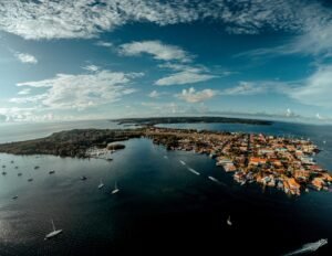 Stunning aerial view of a coastal town with marinas and yachts in a tropical island setting.