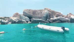 A tranquil scene featuring a boat and rocky shoreline at The Baths, British Virgin Islands.