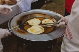 People cooking traditional fried dough outdoors in Croatia.
