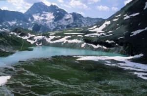 Breathtaking alpine lake in Pralognan-la-Vanoise, France with snowy mountains and lush landscape.