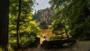 A scenic view of Externsteine rock formation surrounded by lush greenery in summer.