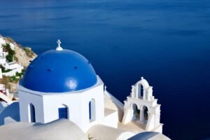 Breathtaking view of Santorini's blue-domed church overlooking the Aegean Sea, capturing Greek architecture.