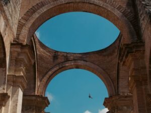 Elegant ancient brick arches of a historic ruin in Antígua, Guatemala, under a clear blue sky.