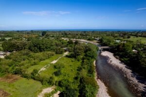 Aerial view capturing the lush green landscape and river near La Ceiba, Honduras, meeting the ocean.