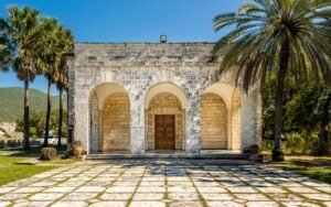 Old stone structure with arched entrance surrounded by palm trees in Kingston, Jamaica.