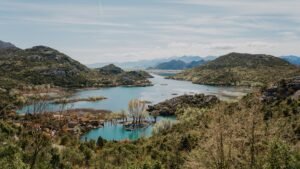 Serene mountain landscape with a tranquil lake surrounded by lush greenery and hills.