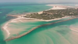 Stunning aerial view of a tropical island surrounded by turquoise waves and white sand beaches.