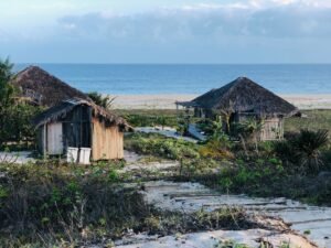 Idyllic tropical huts with thatched roofs on a serene beach setting, ocean in view.