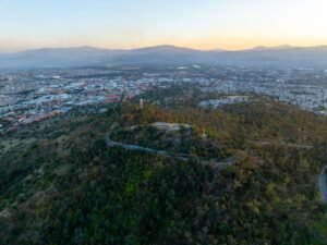Stunning aerial view of Ciudad de México with mountains at sunset, showcasing urban and natural landscapes.
