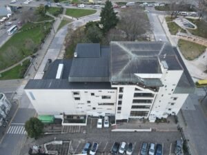 Aerial perspective of a modern urban building with adjacent parking and city streets.
