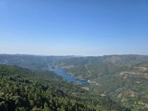 Stunning aerial view of a river winding through lush green mountains under a clear blue sky.