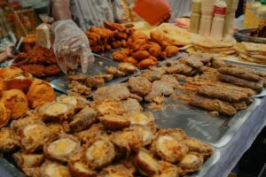 A variety of traditional foods displayed at a bustling Dhaka Iftar market during Ramadan.
