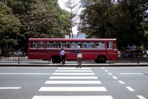 A red public bus waiting at a zebra crossing on a city street in Sri Lanka.