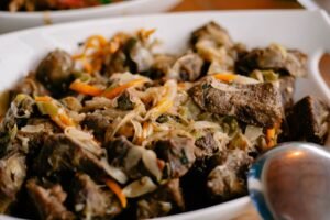 Close-up of a flavorful beef stir-fry with mixed vegetables in a white serving dish, perfect for dinner.